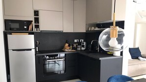 Une cuisine moderne équipée d’un four encastré, d’un four à micro-ondes et d’un réfrigérateur à porte vitrée.