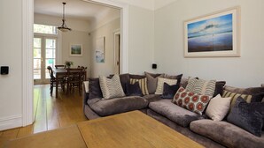 Una sala de estar con un sofá modular, una mesa de centro de madera y un comedor con sillas y una mesa.