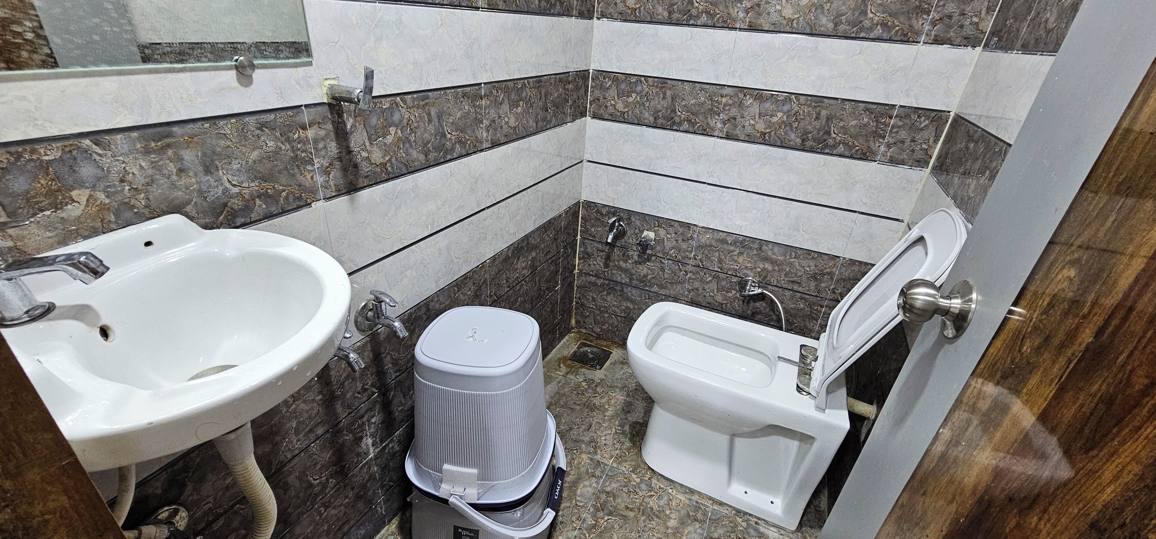 Un baño pequeño con lavamanos, inodoro y cubo de basura.