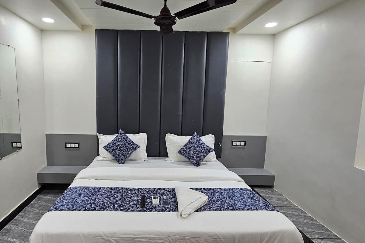 A modern hotel room with a large bed, a ceiling fan, and a dark headboard.
