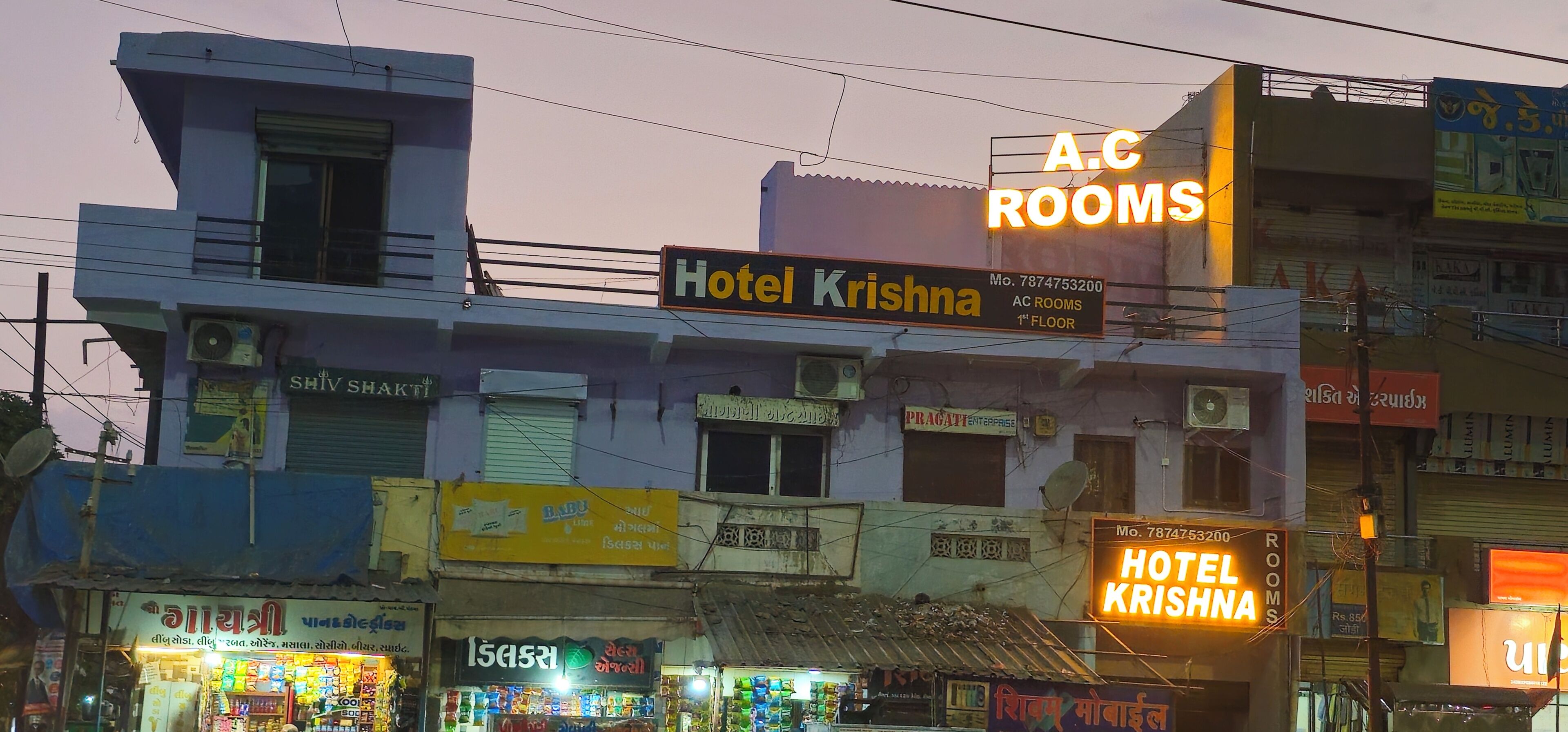 A multi-story building with signage for 'Hotel Krishna' and 'A.C Rooms' on the 1st floor.