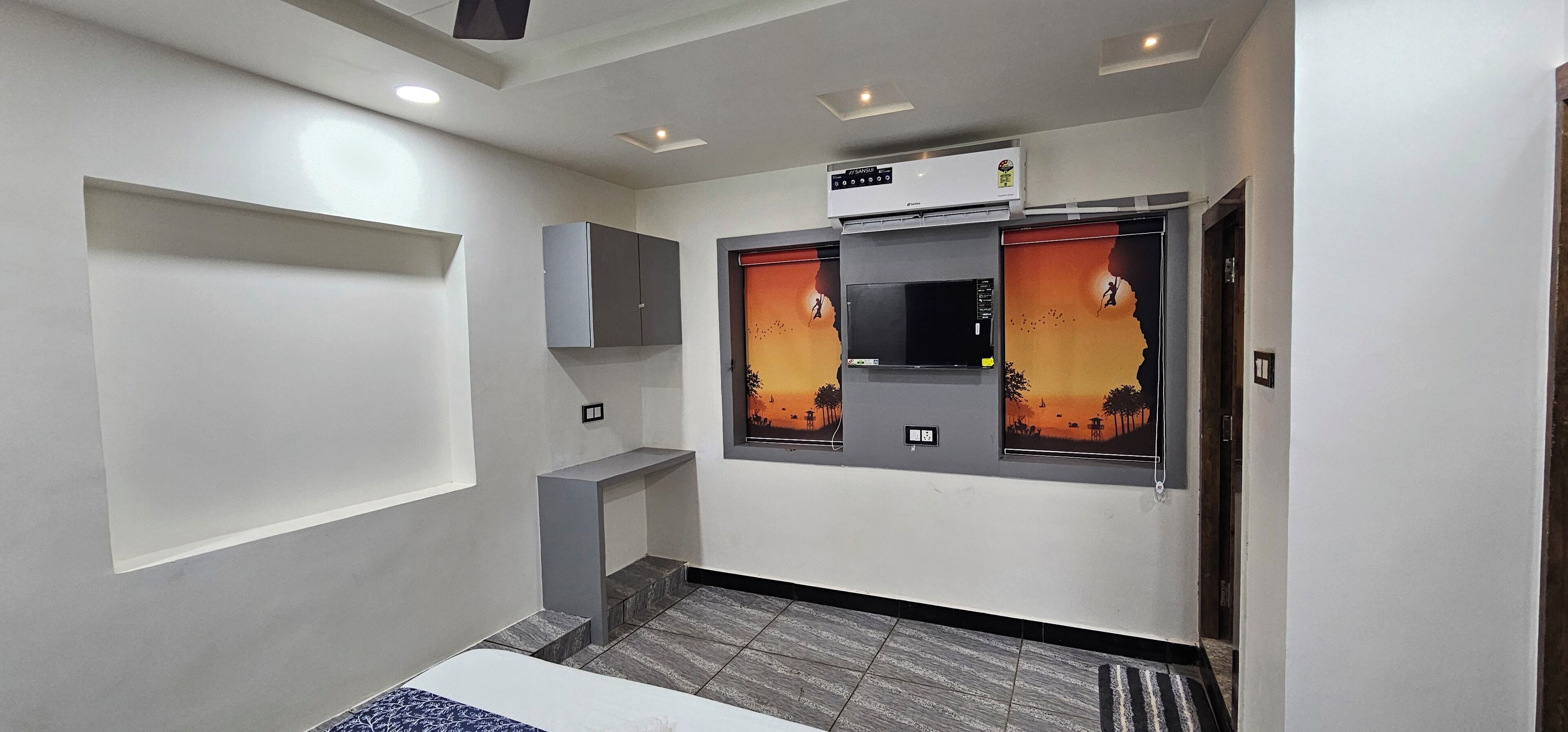 Hotelkamer met een bed, een garderobe, een ingebouwde airconditioning en een raam met uitzicht op een zonsondergang.
