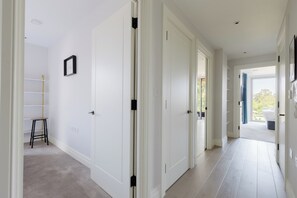A hallway with white doors, a small stool, and a picture frame on the wall. - Modern Parkside Flat with Balcony in Kilburn (Greater London)