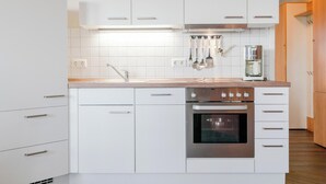 A modern kitchen with white cabinetry, stainless steel appliances, and a wooden countertop. - Ferienwohnung im 3.OG mit Balkon in Sellin (Sellin)