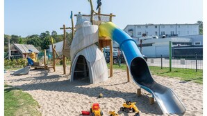 Een speeltuin met een glijbaan, klimconstructies en zand.