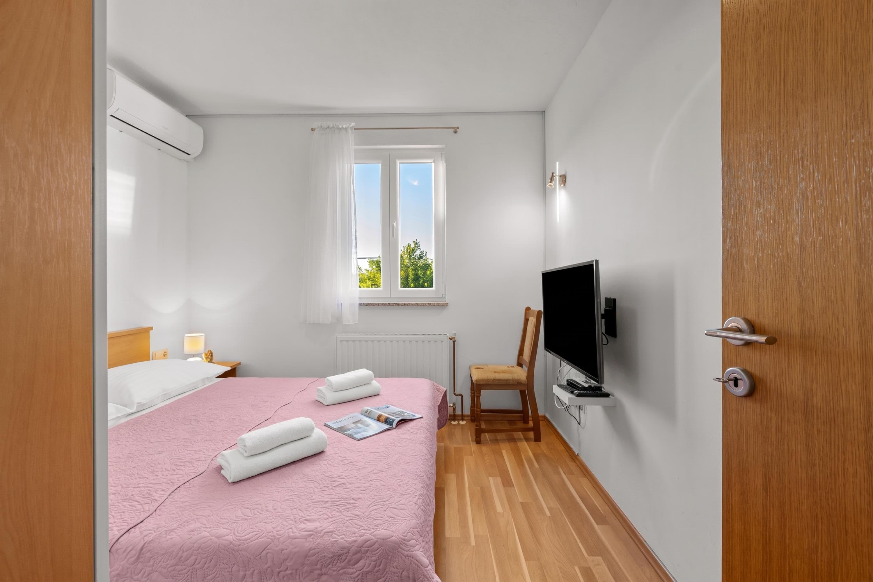 Une chambre d’hôtel avec un lit, une télévision, une chaise et une fenêtre.