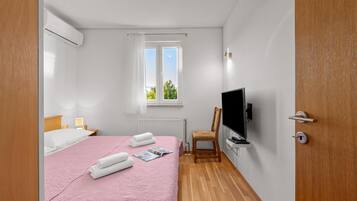 A hotel room with a bed, a television, a chair, and a window.