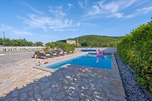 Una piscina con sillones de descanso y un flotador con forma de flamenco rosa.