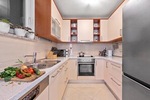 Una cocina moderna con un refrigerador de acero inoxidable, un horno y un lavamanos.