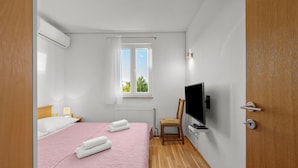 A bedroom with a bed, a chair, a TV, and a window. - Pool Villa Marija (Unesic)