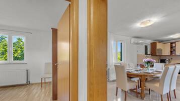 A modern kitchen with white cabinets, a dining table set for four, and a view of the outdoors.