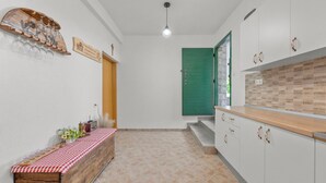 A kitchen with a wooden countertop, white cabinets, a green door, and a bench with a checkered tablecloth. - Pool Villa Marija (Unesic)