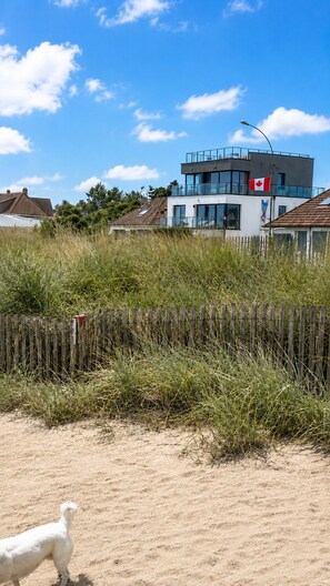 Ein modernes Gebäude mit kanadischer Flagge, umgeben von hohem Gras und einem Holzzaun.
