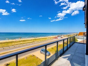 Ein Balkon mit Blick auf einen Strand und eine Straße.