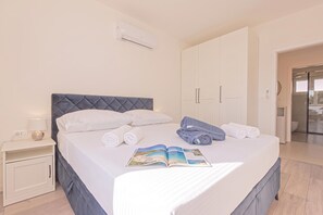 A neatly made bed with pillows, a bedside lamp, and rolled towels. - Pool Villa Pomalo (Vodice)