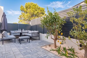 An outdoor patio with a grey sofa set, a table, and a small tree with yellow fruit. - Pool Villa Pomalo (Vodice)