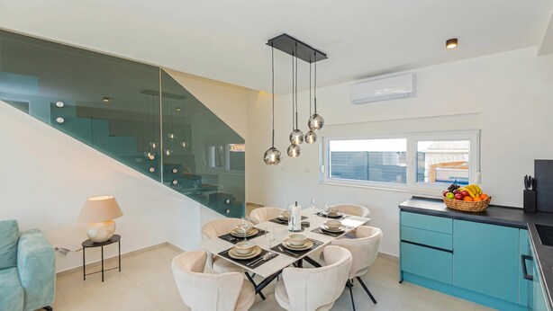 A modern kitchen with a dining area, a staircase, and a view of the outside. - Pool Villa Pomalo (Vodice)