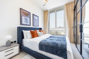 Um quarto moderno com uma cama, mesa de cabeceira e janela com cortinas.