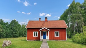 A red wooden house with a blue door, white windows, and a gravel path leading to the entrance. - Nice home in Ryssby with house a panoramic view (Ryssby)