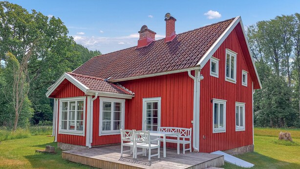 A red wooden house with a tiled roof, a porch with white furniture, and a grassy yard. - Nice home in Ryssby with house a panoramic view (Ryssby)