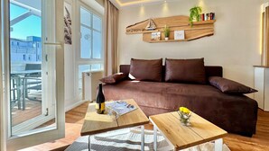 Een moderne woonkamer met een bruine bank, houten salontafels en een groot raam.