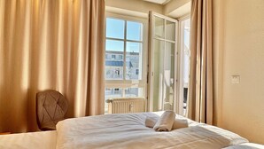 Een hotelkamer met een bed, een stoel, een raam en uitzicht op gebouwen.