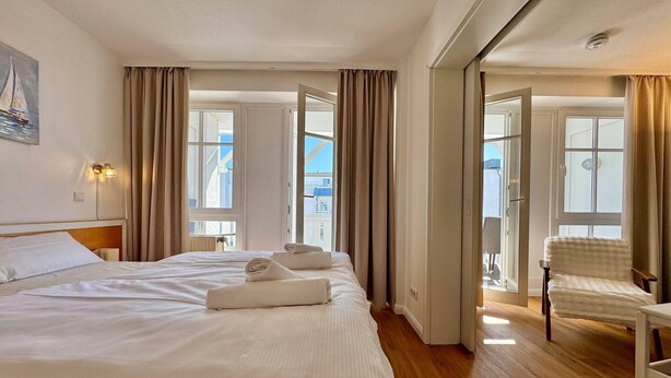 Een hotelkamer met een groot bed, een stoel, een schilderij en uitzicht.