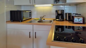 Ett kök med mikrovågsugn, brödrost, kaffebryggare, diskho och spis.