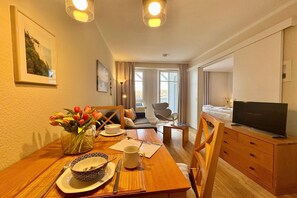 Ein Hotelzimmer mit Essplatz, Fernseher, Sofa und einem großen Fenster.