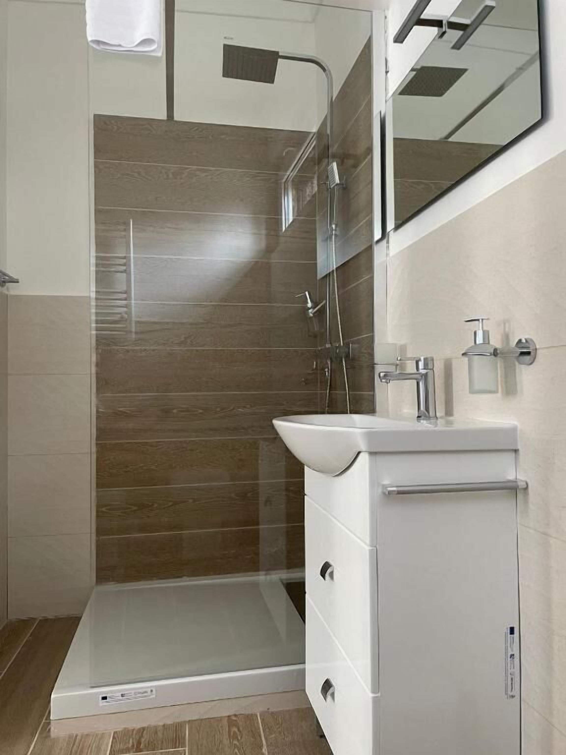 Une salle de bain moderne avec une douche, un lavabo et un miroir.