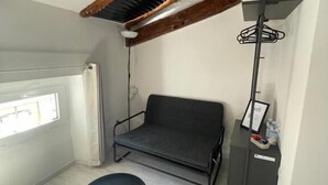 A small room with a loft bed, a black chair, a desk with a lamp, and a window. - L'impronta (Gorizia)