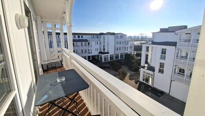 En balkon med bord og stole, der giver udsigt over en række hvide bygninger med balkoner.