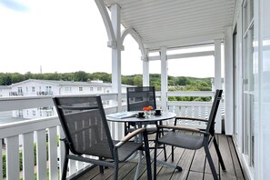 A balcony with a table, chairs, and a view of buildings and greenery. - Moderne Ferienwohnung mit Balkon und WLAN in Sellin (Sellin)
