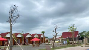A poolside area with lounge chairs, a swimming pool, and red-roofed cabins.