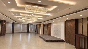 Un amplio vestíbulo de hotel con techo alto, múltiples candelabros y suelo de mármol.