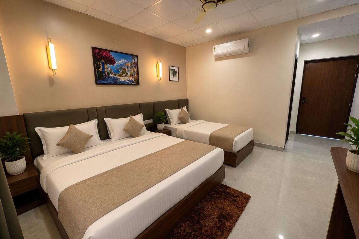 A hotel room with two beds, a ceiling fan, wall-mounted air conditioning, and a painting.