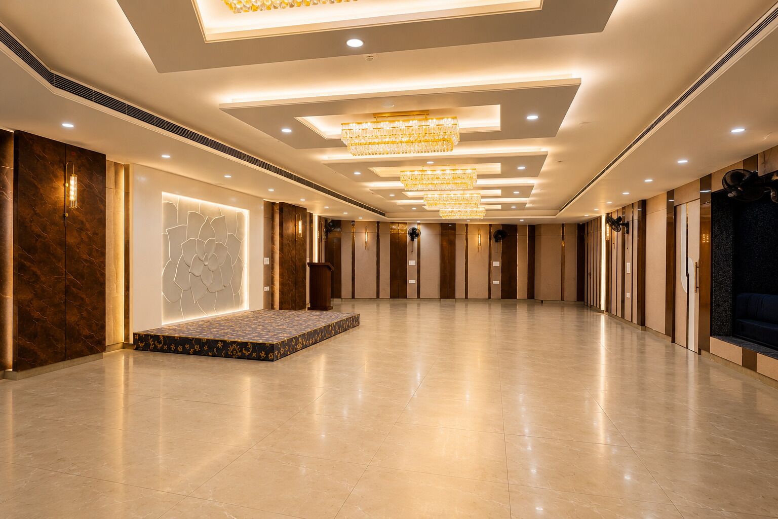 Un amplio vestíbulo de hotel con un escenario, candelabros y suelo de mármol.
