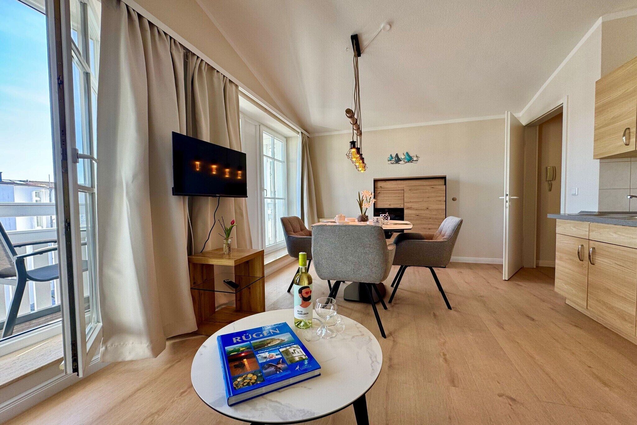 Ein modernes Wohnzimmer mit Essbereich, einem an der Wand montierten Fernseher und einem Buch auf einem Tisch.
