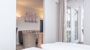 Ett hotellrum med en säng, en soffa, en TV och en skjutdörr i glas som leder ut till utsidan.