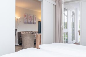 Ein Hotelzimmer mit Bett, einer Couch, einem Fernseher und einer Schiebetür zum Außenbereich.