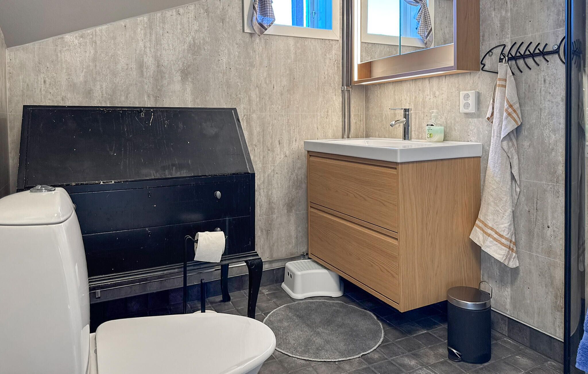 A bathroom with a toilet, a sink, a mirror, and a shower area.