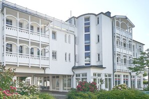 Ein mehrstöckiges Hotel mit Balkonen, großen Fenstern und einem Garten mit Blumen.