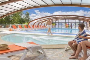 An indoor swimming pool with a covered area, lounge chairs, and a clear view of the sky. - Mobile home near Château de Chaumont (Onzain)