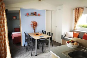 A compact living space with a dining area, kitchenette, and a sofa with cushions. - Mobile home near Château de Chaumont (Onzain)