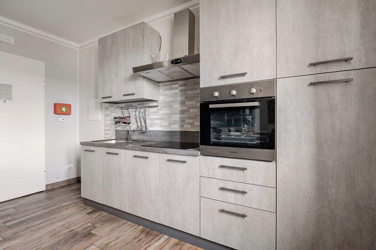 Una cucina moderna con mobili grigi, un forno in acciaio inossidabile e un microonde integrato.