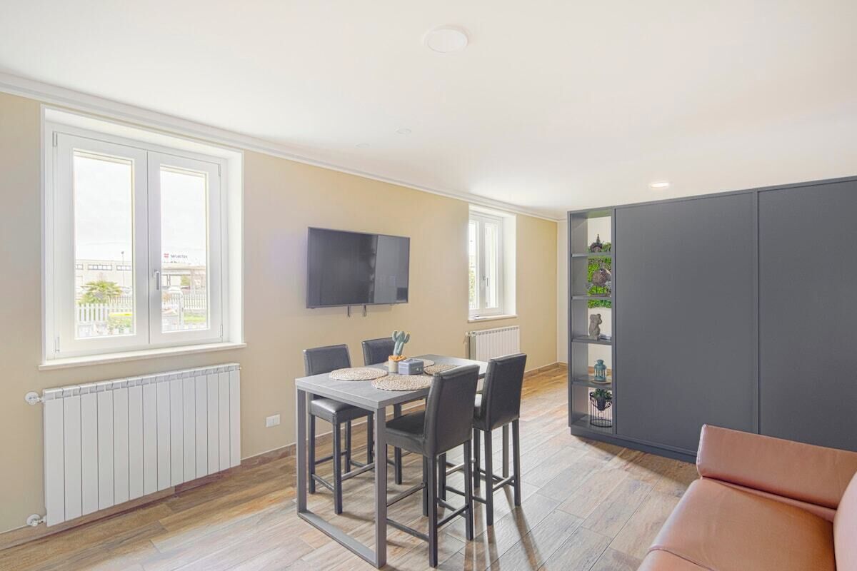 Ein modernes Wohnzimmer mit Essbereich, einem an der Wand befestigten Flachbildfernseher und einer großen grauen Kommode.
