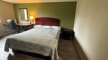 A hotel room with a bed, a desk, a chair, and a nightstand.