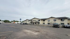 A parking lot with several cars, a building with multiple windows, and a sign in the distance. - 2 Full Beds | Non-Smoking (Coldwater, MI)