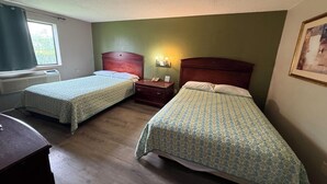 A room with two beds, a nightstand, a lamp, and a window with curtains. - 2 Full Beds | Non-Smoking (Coldwater, MI)