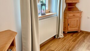 Habitación con ventana, armario de madera, radiador y suelo de madera.